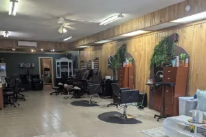 Interior of Hidden Beauty Studio salon with multiple styling chairs, mirrors, and hairdressing stations in a warmly lit room